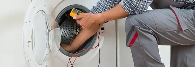 Dryer repair technician inspecting and repairing a clothes dryer in Bloomington, IN