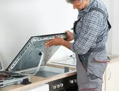 Appliance repair technician installing a built-in cooktop in Bloomington, IN