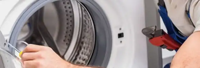 Appliance technician repairing a clothes dryer drum and internal parts in Bloomington, IN