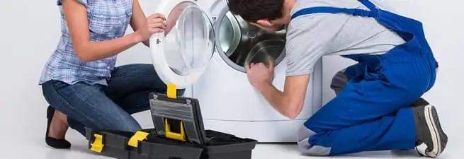 Washer repair technician inspecting a front-load washing machine with tools in Bloomington, IN