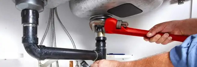 Garbage disposal repair technician tightening the sink drain and disposal connection in Bloomington, IN