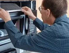 Appliance repair technician replacing a microwave vent filter in Bloomington, IN