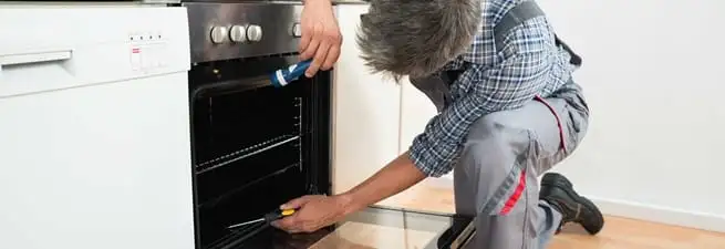 Oven repair technician inspecting and servicing an electric oven in Bloomington, IN