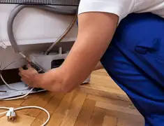 Appliance repair technician fixing refrigerator water line and connections in Bloomington, IN