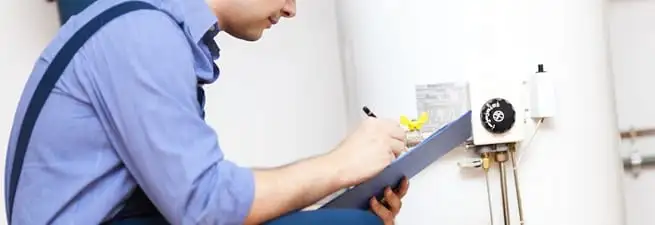 Water heater repair technician inspecting the unit and recording service notes in Bloomington, IN
