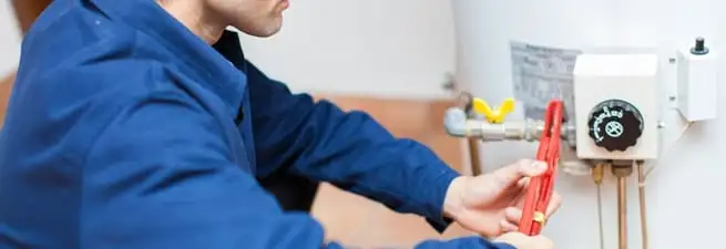 Water heater repair technician adjusting the temperature control and gas valve in Bloomington, IN